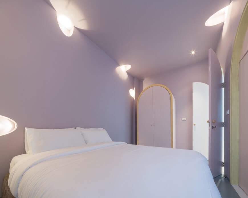 在真正的洋葱时尚，干净的线条和简单的颜色展示在这个房间。薰衣草色的墙壁和明亮的白色——在床上和灯光上——创造了一个干净和欢迎的氛围。没有床头板让房间感觉简单和简约。