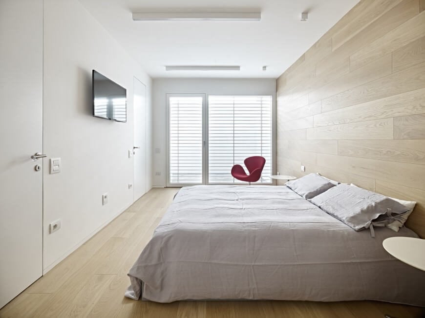 这面华丽的木质强调墙取代了床头板，将木地板带到墙上，突出了简单的床和家具的选择。这种极简的设计将被一个笨重的床头板所取代。