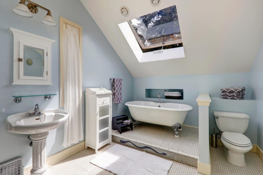 这个浴室设有一个大天窗，让新鲜空气和自然阳光涌入房间。爪足浴缸是高架的，并塞在倾斜的天花板下，创造了一个舒适而隐蔽的空间。