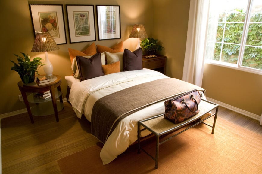 再次使用装饰性的枕头来代替床头板，这个棕色和橙色的卧室在米色和棕褐色的背景下形成了一个令人惊叹的颜色组合。