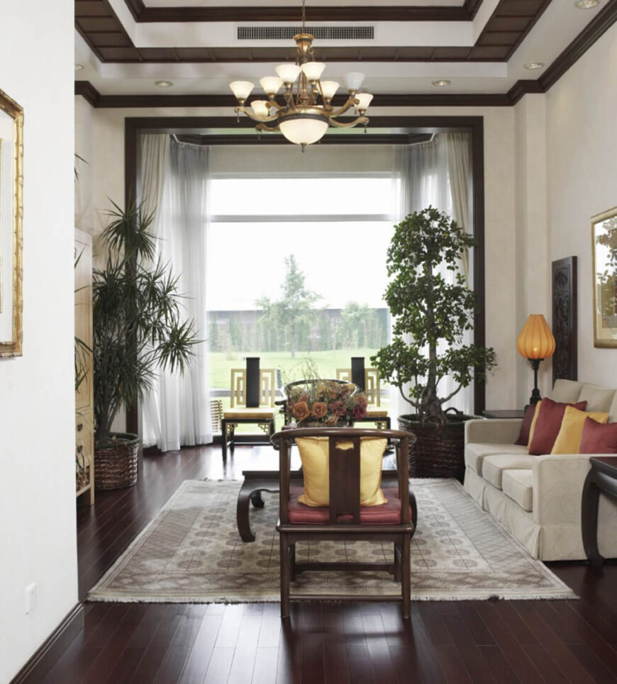 通过选择室内植物，房间的东方风格得到了加强。浓郁的酒红色和金色突出了木地板和配套家具的华丽红色色调。