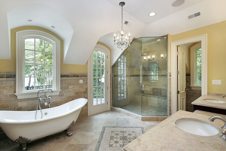 这间宽敞的浴室设有一个大的角落淋浴间，带有独特的角度天花板。地板上的时间在整个房间的墙壁上延伸了一半，爪足浴缸在一扇十二窗格的窗户下有自己的空间。