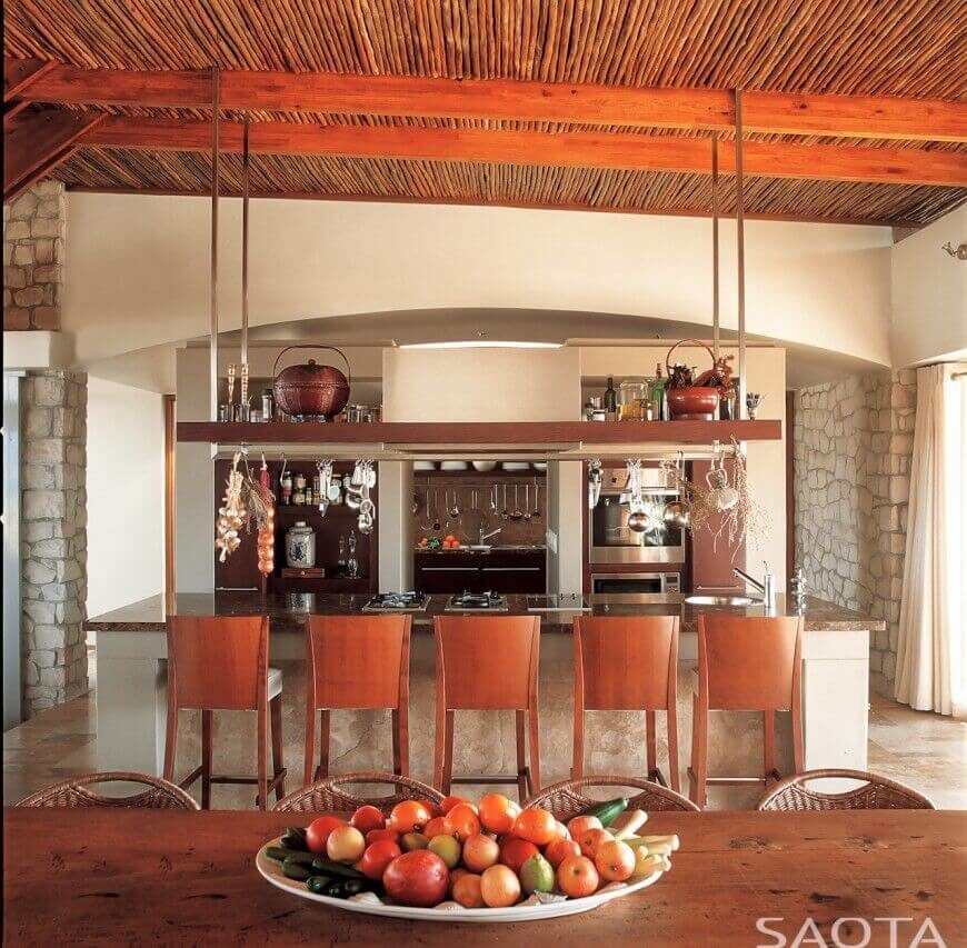 一个可爱的厨房与石头口音和乡村的当代氛围。在漫长的岛屿上方是一个大的锅架，上面放着干燥的草药。