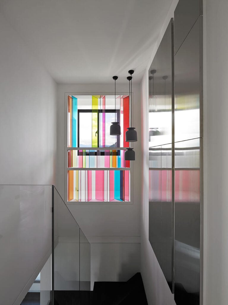 楼梯的另一边利用了大窗户的优势，为空间带来了鲜艳的色彩。透过彩色玻璃的光线在原本平淡的墙壁上创造出美丽的色彩。