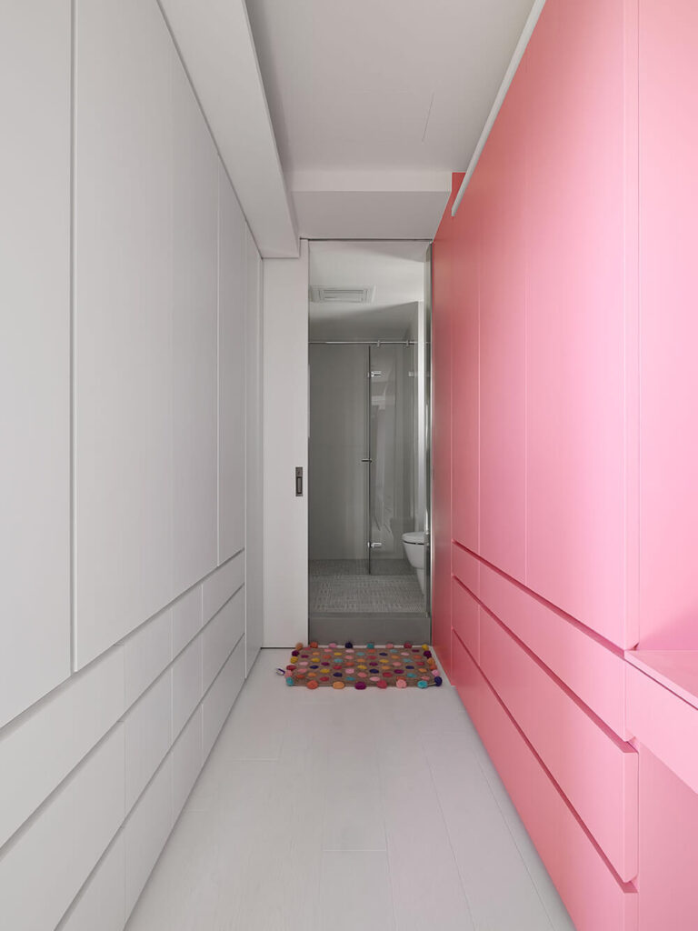 孩子房间里的衣柜。整个房间都被装饰成白色和淡粉色，就像衣柜里展示的那样。它们的设计和空间完全相同，尽管颜色不同。在它们后面，你可以看到附属的浴室。