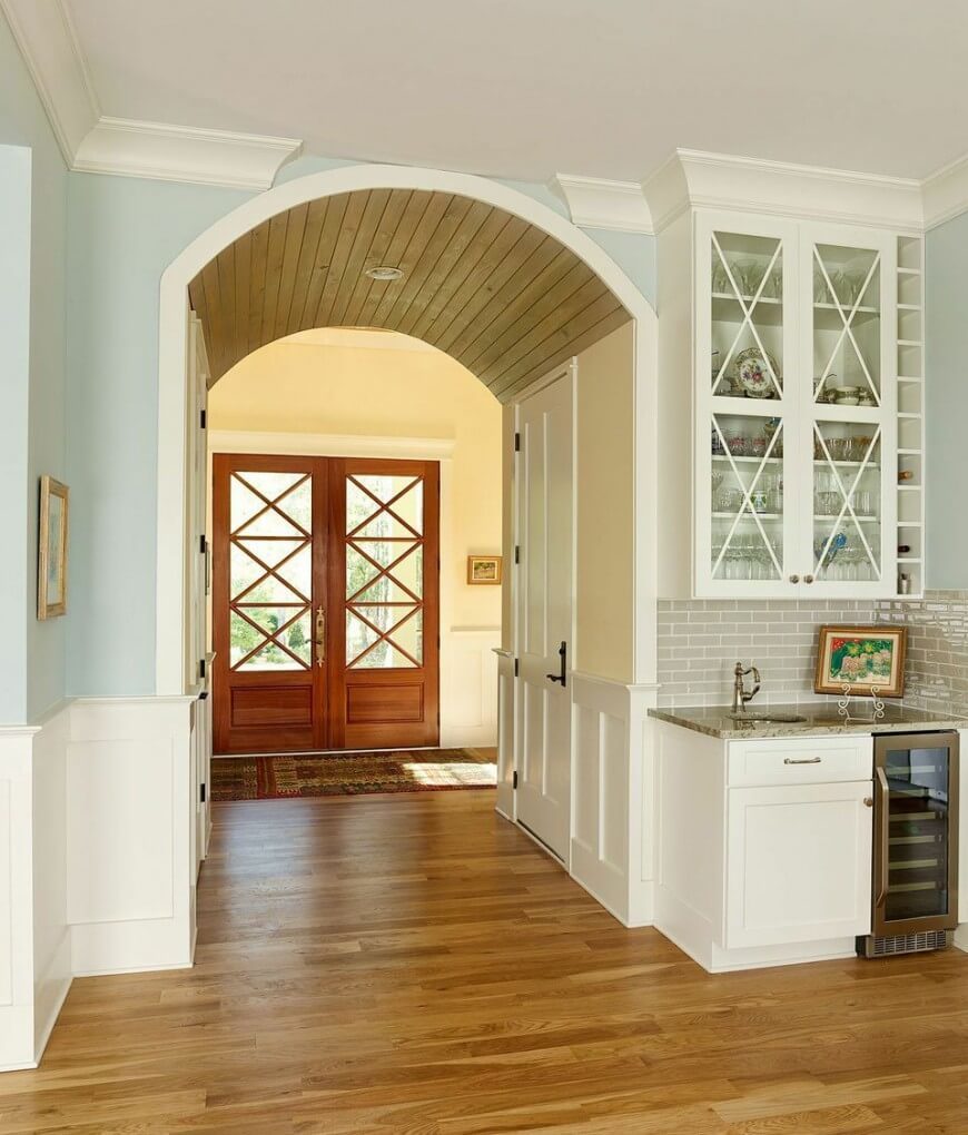 构成拱门天花板的木条为这个房间带来了独特的触感，很好地框定了双前门。厨房里使用淡黄色的墙壁，让位于明亮而平静的蓝色，创造了迷人的色彩组合，而门前地毯的丰富色彩为空间带来了更多。