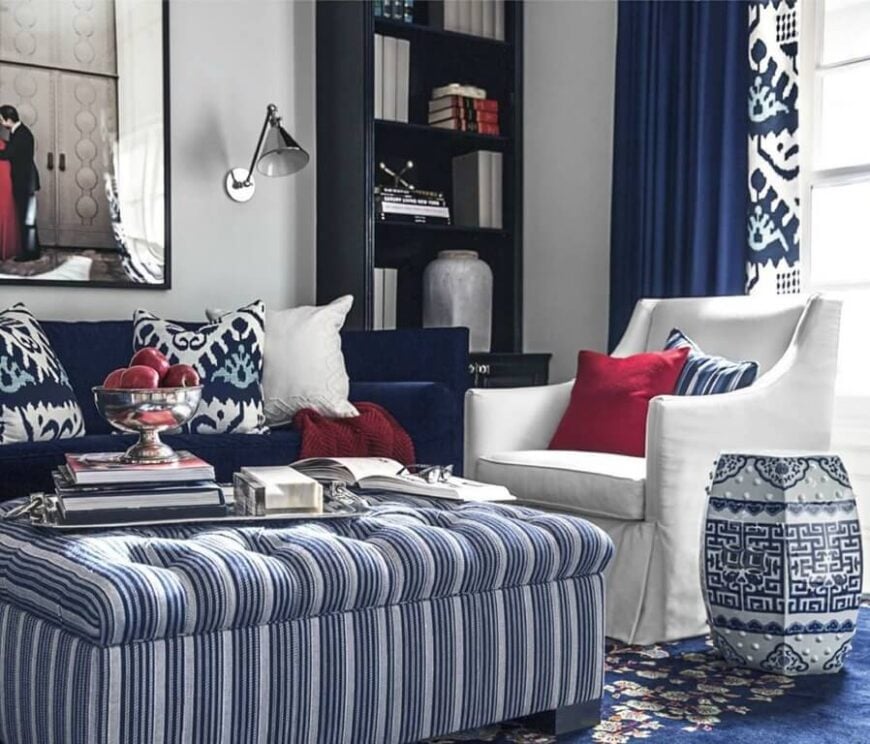 一个统一的蓝色和白色的配色方案把这个客厅联系在一起，中心是一个大的纽扣簇垫脚凳。右边的白色扶手椅与蓝色沙发相得益彰。