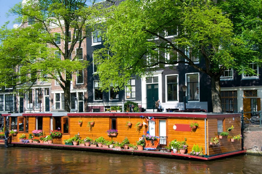 一艘非常长的船屋，有木制壁板，到处都是成吨的花园容器。这座可爱的永久住宅是阿姆斯特丹2400所房屋中的一所。