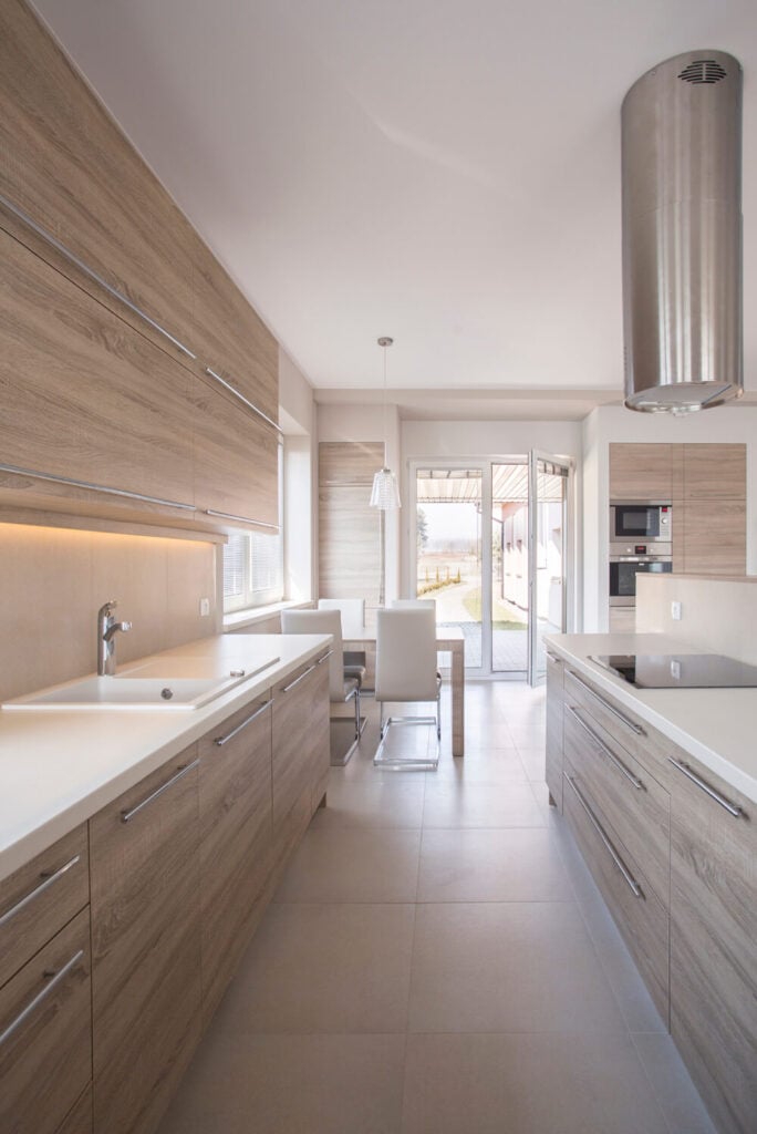 厨房橱柜的灰色调，与白色台面、后挡板和瓷砖相结合，创造了一个明亮的厨房，使厨房的空间感觉更加开放。