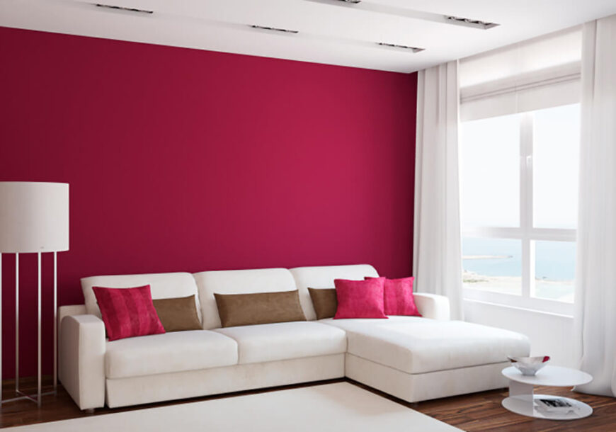这间客厅很简单，但充满活力。亮粉色的枕头与白色沙发和地毯形成鲜明对比，而沙发后面的粉色墙壁给房间带来了强烈的个性感。在这里，缺乏墙壁装饰本身就是一种陈述。