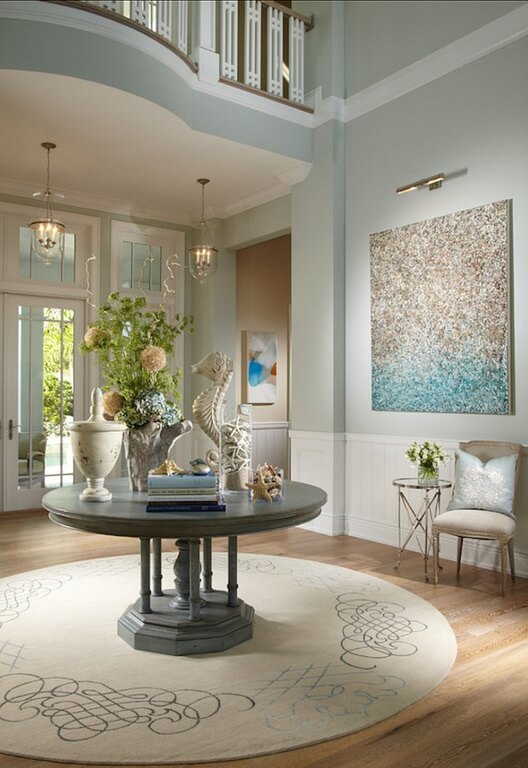这个房间中浅色的使用成功地创造了这个设计的航海主题。淡蓝色的墙壁以微妙的风格贯穿整个房间，比如枕头，或者中间桌子上的插花。白色的护墙板突出了米色和灰白色，可以更好地衬托出蓝色和桃子。