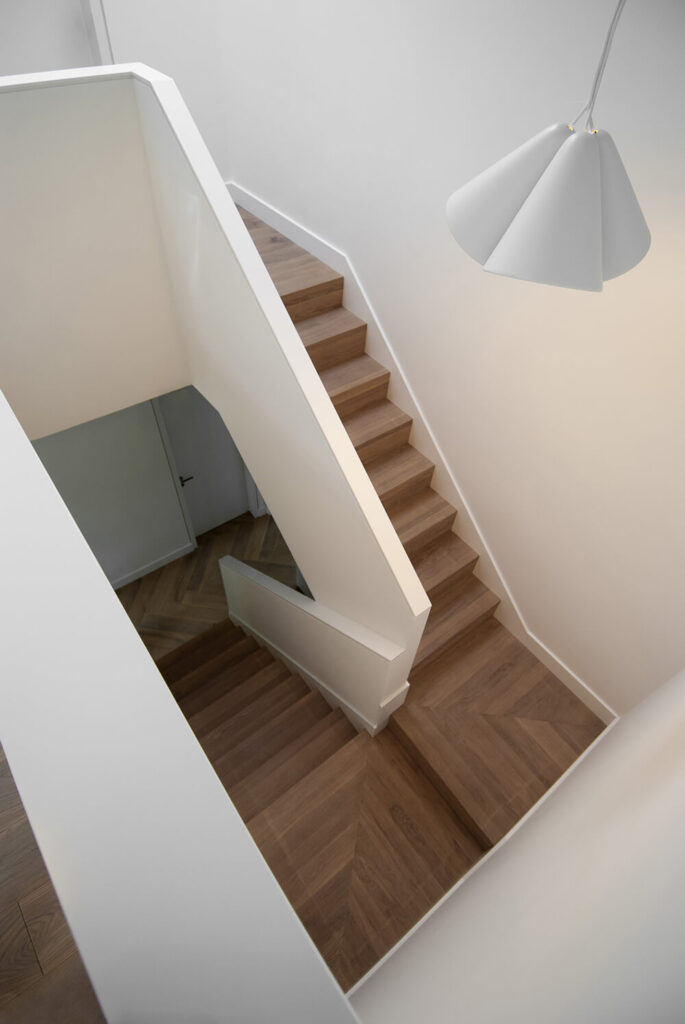 通往二楼的楼梯改变了楼层的材料，在楼层之间过渡。白色的墙壁保持了简单的风格，而木地板的加入使房子的睡眠区域的空间变暖。简单的白色吊灯点亮了整个空间。