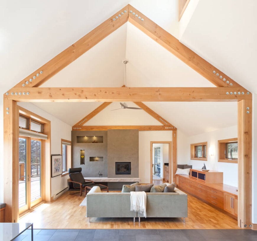 走进室内，我们可以看到丰富的天然木材是如何体现整个设计的。天然木梁穿过客厅的白色拱形天花板。