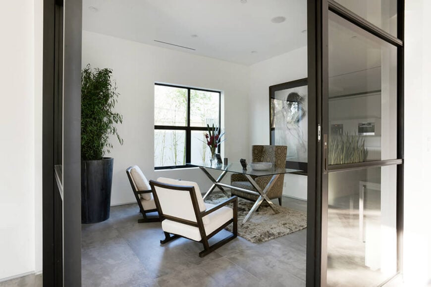 这个家还包括一个办公空间，配有时尚的设计师椅子和时尚的现代玻璃桌子。白色和黑色的配色方案使空间既专业又舒适。大毛绒地毯也赞美周围的地板。