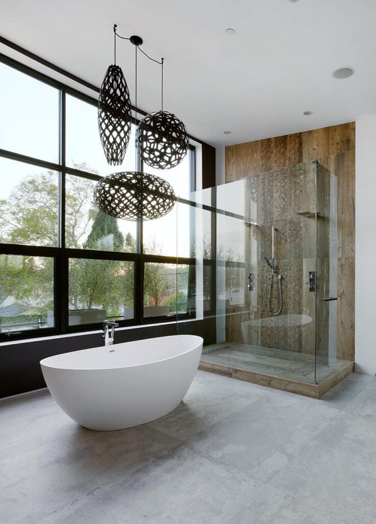 浴室空间还设有一个复杂的浴缸，设置在一面墙的窗户前，提供了一个视野。步入式淋浴间被玻璃包围，内部以木纹为特色，与浴室的其他部分形成对比。