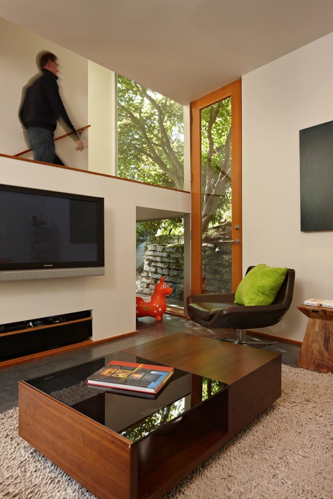 在塔的一层是客厅，它的特点是一个舒适的地毯，一个大电视，和一个现代风格的咖啡桌。透过半面墙可以看到通往下一层的楼梯井。