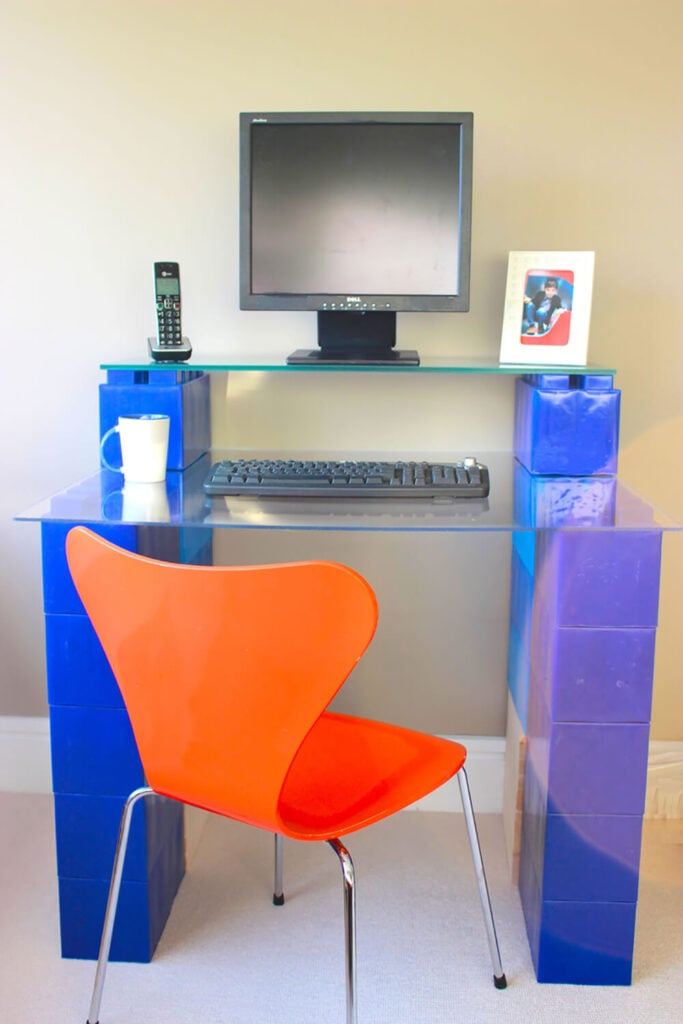 这里有一个真正新颖的想法:用亮蓝色的EverBlocks制作一个全尺寸的双层电脑桌。通过简单地添加一对玻璃面板，这些街区立即转变为有用的工作空间。