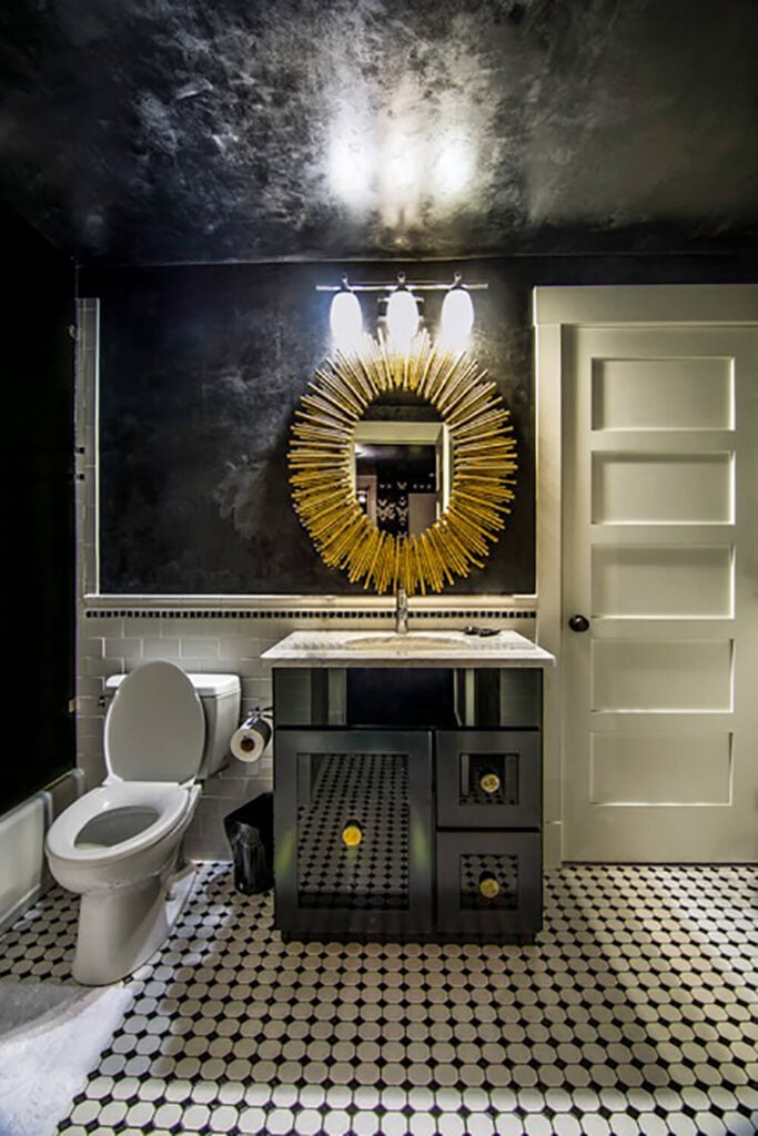 这个较小的浴室是一个高对比度的练习，黑白瓷砖地板反映了墙壁和天花板的调色板。一个简单的黑色梳妆台，顶部是大理石，下面是一面向日葵形的镜子。