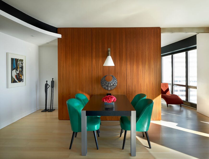 距离厨房和客厅仅几步之遥的是一间舒适的现代餐厅，餐厅与书房隔着一面与厨房橱柜相配的胡桃木墙。翡翠绿的餐椅为设计增添了大胆的色彩。
