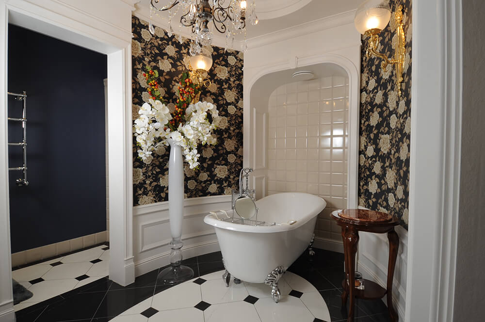 这款浴室拥有优雅的墙壁和室内花的花瓶，墙照明点亮。瓷砖地板看起来也很优雅。