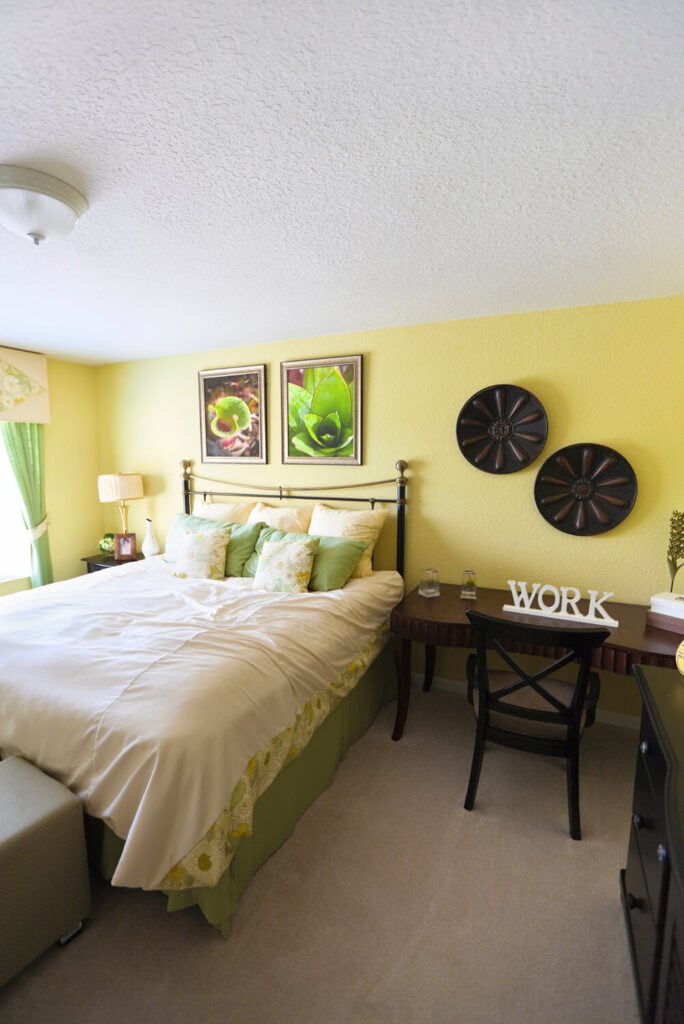 自然光照进这间卧室，照亮了柔软的绿色墙壁和白色床罩。深色的木质装饰和家具有助于平衡浅绿色的色调。办公桌就放在床的一边，有足够的空间来移动，保持舒适。
