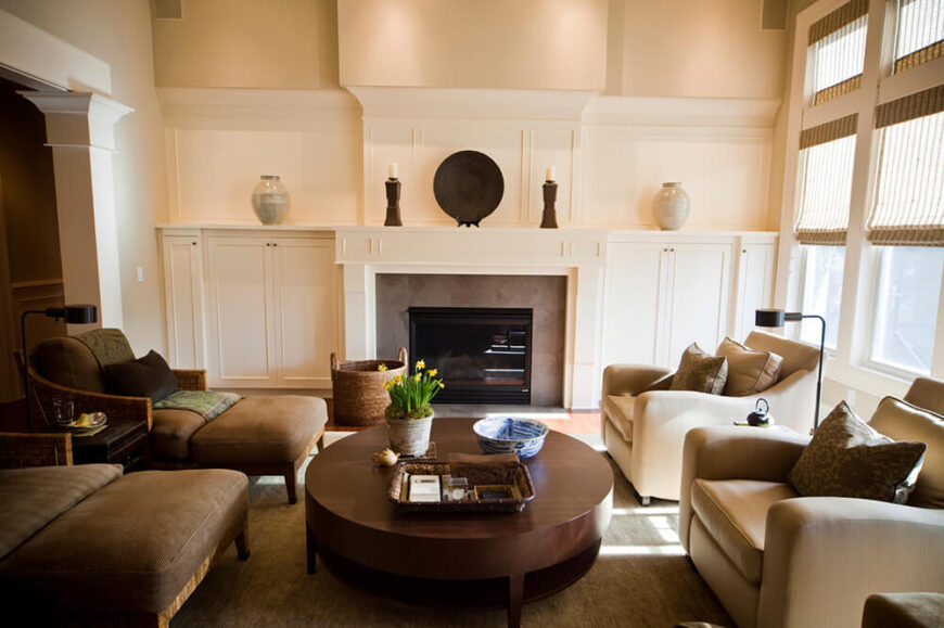 这间客厅以米黄色的墙壁和一些深色家具为特色，有助于赋予房间深度。填充躺椅环绕着一个大的木制咖啡桌，而从窗户进来的自然光有助于照亮房间。