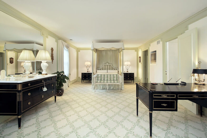 宽敞的卧室空间，配色适中。浅石灰绿色的色调构成了地毯上、床周围和墙壁上的图案。黑色的抽屉和桌子形成了强烈的对比，而房间里其余的白色则平衡了一切。金色装饰沿书桌和抽屉建议一个帝王的主题，而大雨棚床提供最佳的舒适性。