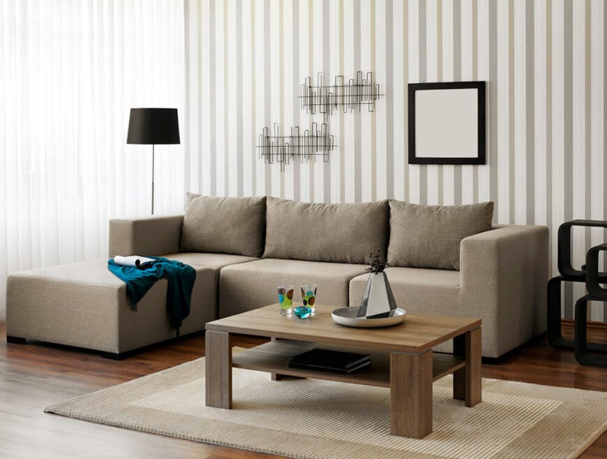 客厅的垂直条纹与中性色调相结合，营造出精致的氛围。深色丰富的木地板与浅色地毯和灰色沙发形成了一点对比。
