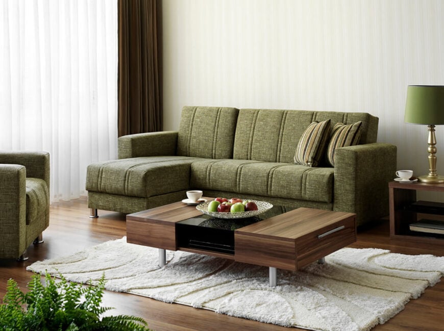 染色的硬木地板与咖啡桌和边桌的地板相匹配。白色长毛绒地毯与深色形成强烈对比，绿色沙发和灯罩平衡了空间。一扇大窗户用自然光照亮了房间。