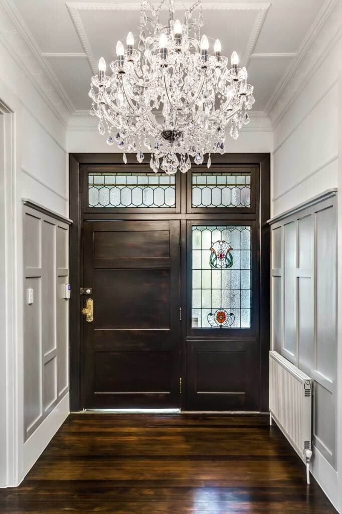 深色染色的硬木地板与入口的前门相匹配。这扇门以其独特的玻璃板为特色。彩色玻璃为这个入口通道提供了恰到好处的色彩。