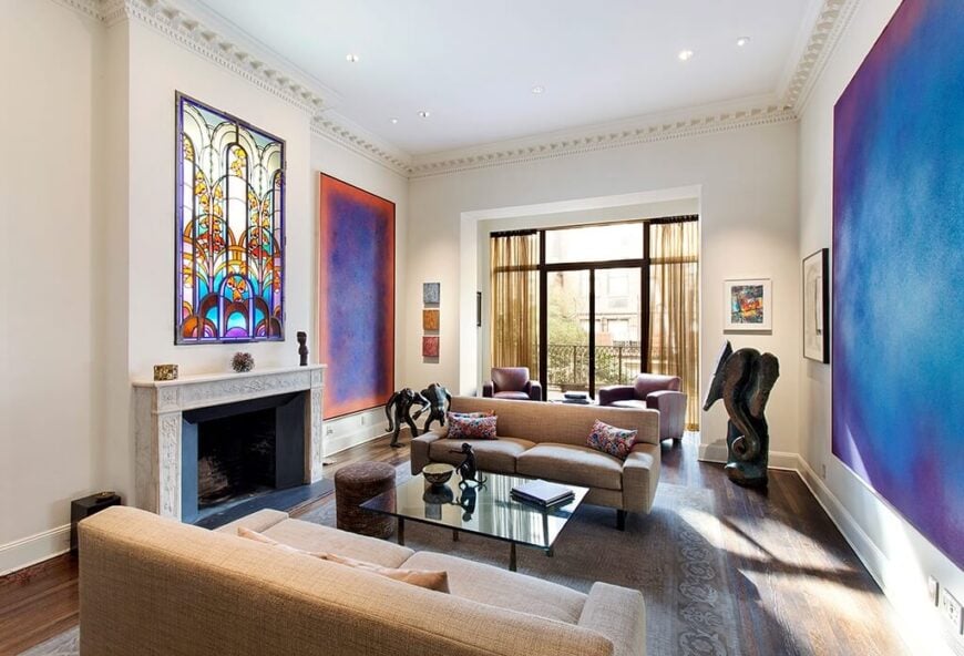 这个客厅有两幅大画，每一幅都为房间提供了大量的色彩。除此之外，壁炉上方还有一扇彩色玻璃窗，为空间增添了复杂的设计元素。