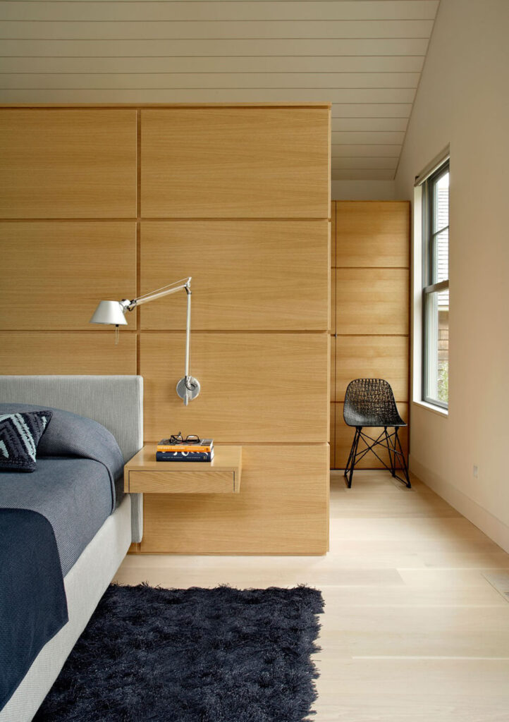 在这所房子的卧室里，轻质硬木地板仍然很普遍。墙壁上有丰富的光泽木镶板，与硬木地板和房间里的深蓝色家具相映成辉。我们可以从独特的床头架子以及安装在墙上的可调节灯中识别出现代风格。