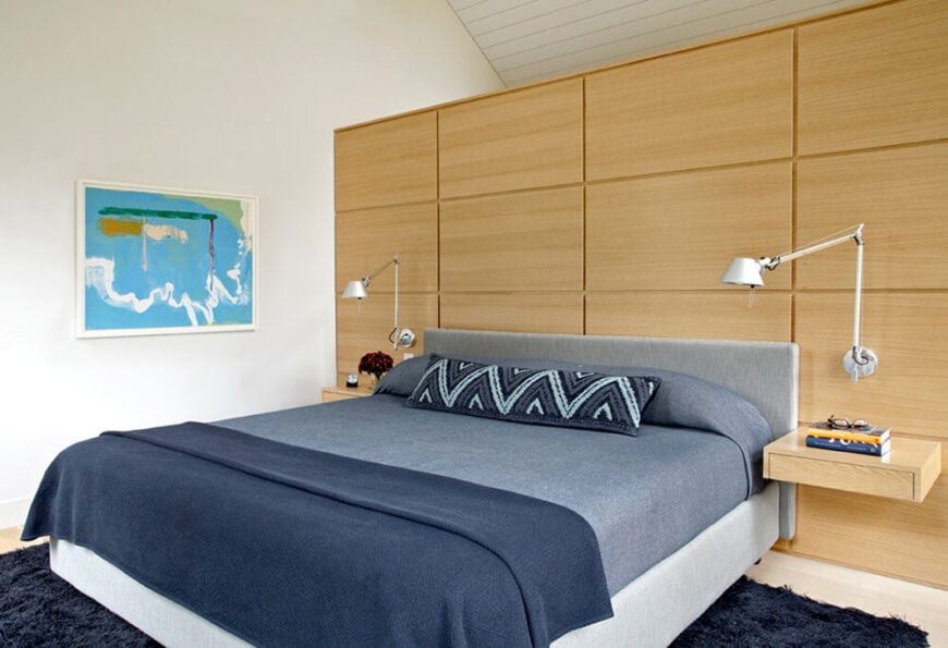 卧室的这个角度显示了整张床，我们会看到床的另一侧有一个匹配的床头架和安装的可调节灯，再一次证明了设计师欣赏对称的美学吸引力。墙上充满活力的蓝色艺术品与房间其他地方的微妙色调形成了鲜明的对比。