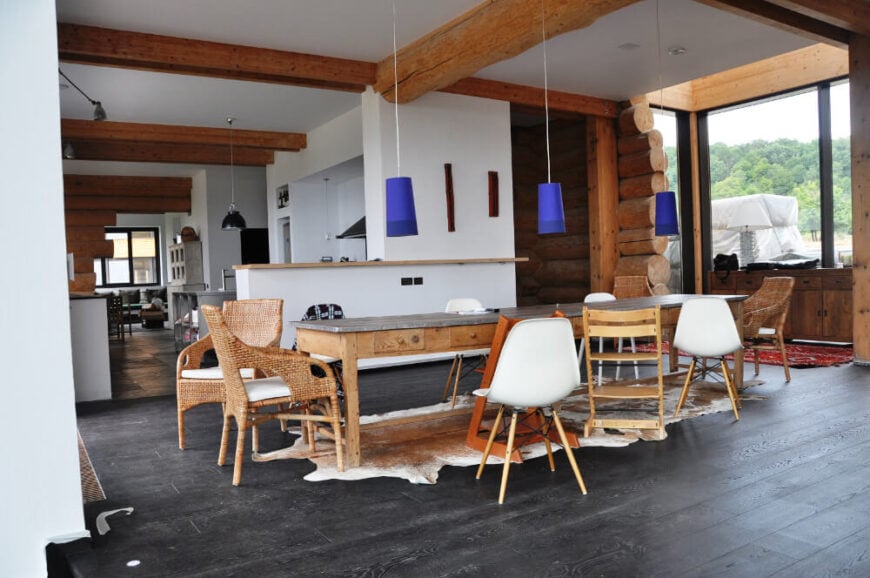 餐厅以一张长长的乡村风格的桌子为中心，周围是各种风格的传统和现代椅子。厨房风格的厨房延伸到左边。