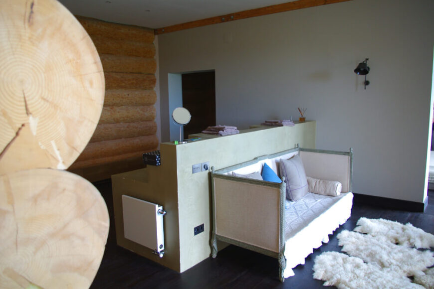 作为卧室套间的一部分，我们看到一个华丽的翻新沙发背靠浴室岛，通过住宅这一侧的大玻璃板自然采光。小木屋的外观延伸到内部的部分，如图所示。