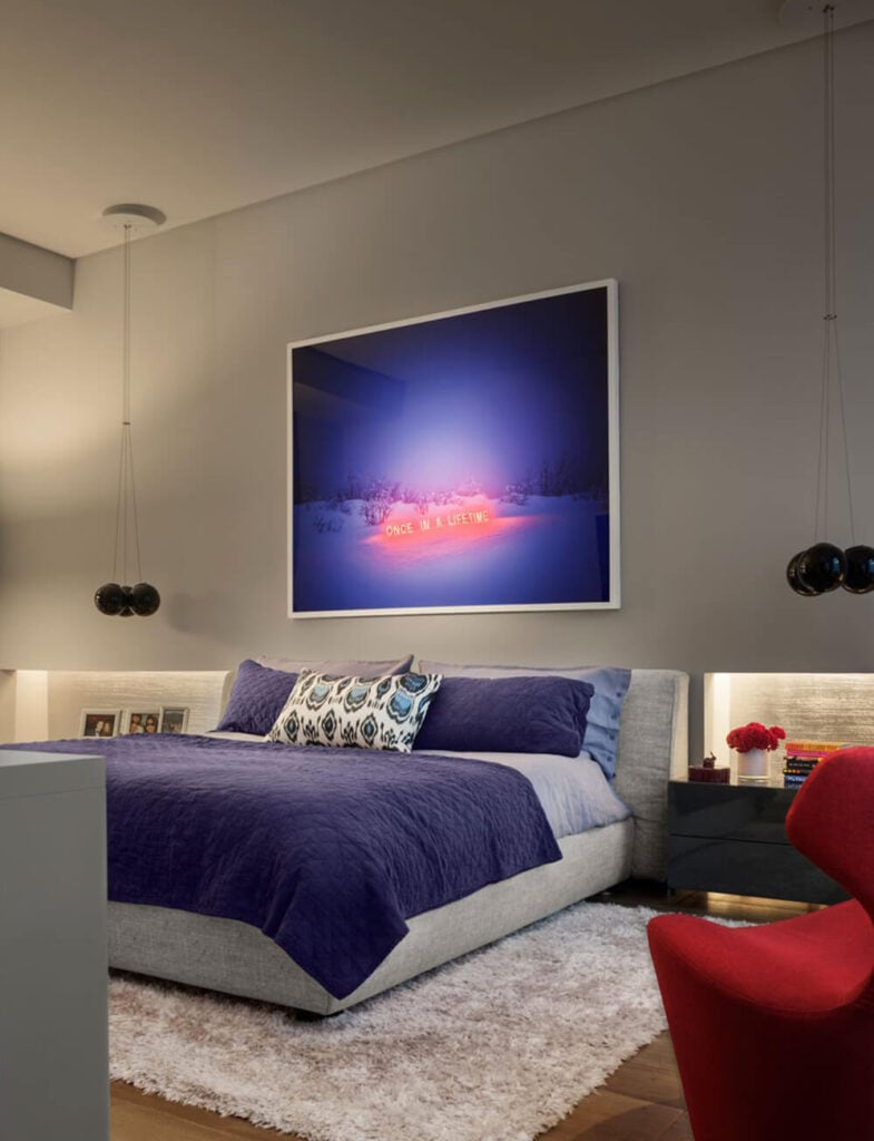 卧室以大胆的颜色为特色，以反映房间的焦点选择的艺术品。丰富的蓝色和大胆的红色使这个房间与房子的其他部分区别开来，而中性的墙壁让这些颜色更加流行。