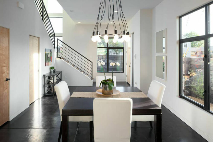 当你进入房子，你马上走进用餐区。纯黑色的地板与白色的墙壁和餐椅形成对比。在入口的正前方，有一个通往二楼的楼梯。