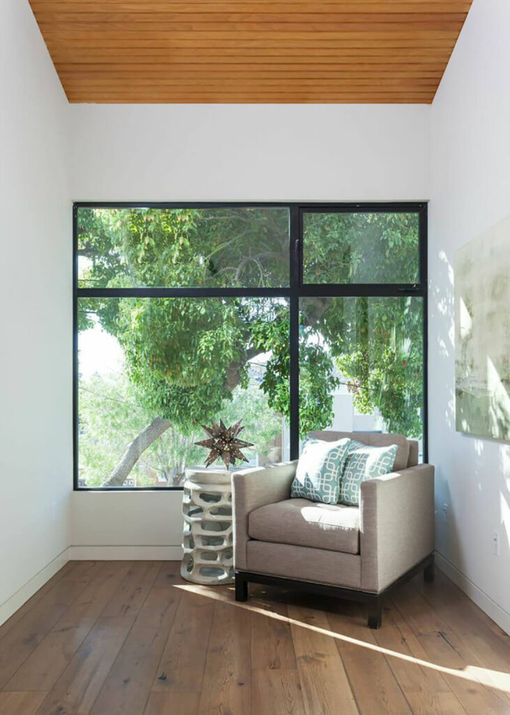 这把躺椅和装饰性的边桌直接放在大窗户旁边，创造了一个坐着享受室内阳光的空间。硬木地板为这个空间营造了一种平静的氛围。