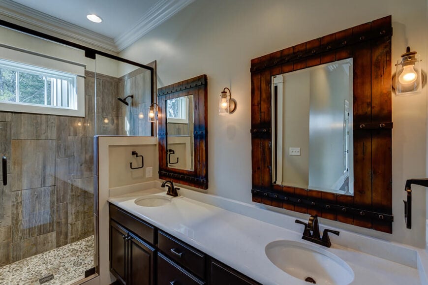主浴室以明亮的白色台面、深色橱柜和更多回收的谷仓木材为特色。质朴的风格和工业风格的灯光贯穿整个房间，与淋浴间的天然石材相辅相成。