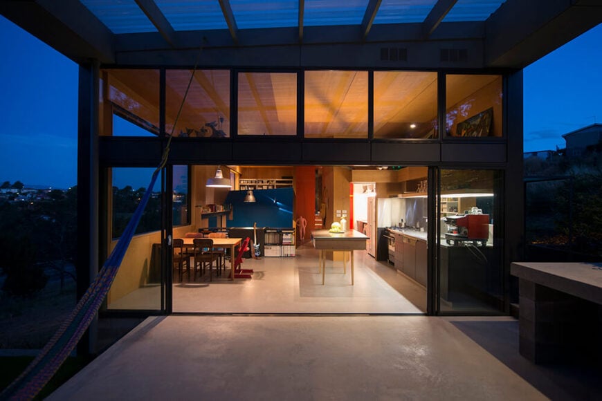 晚上回到室外，我们可以清楚地看到房子和它中心的大型开放空间。在厨房之外，我们看到左边是蓝色的家庭娱乐室，中间是用红色突出显示的楼梯。