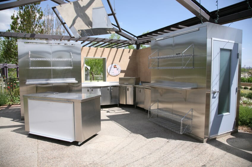 这是一个严肃的室外厨房，配有不锈钢柜台、架子和步入式冰箱。