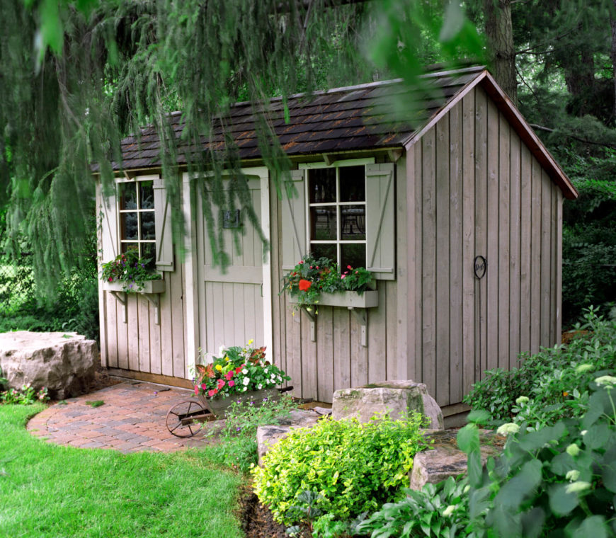 简单的装饰，比如百叶窗、花盆盒和铺路石入口，让这个舒适的花园小屋温暖起来。