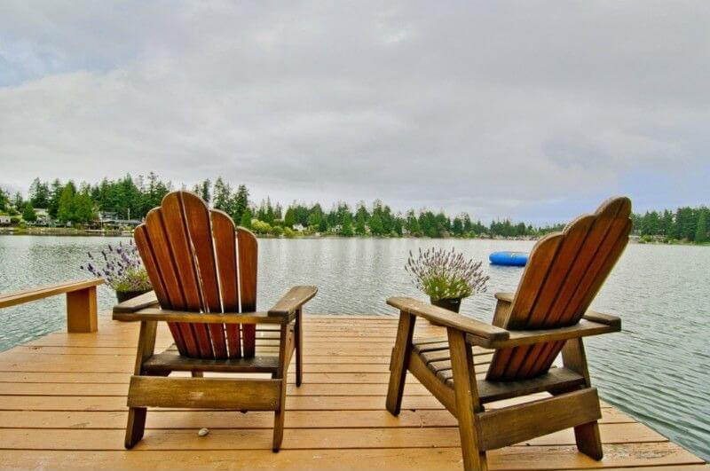 一套阿迪朗达克椅子坐在码头的尽头，里面有两个装满薰衣草的花盆。他们眺望着一个原始平静的湖泊。