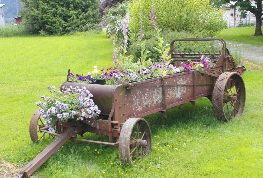 这辆古色古香、锈迹斑斑的马车上摆满了各种各样的花，包括一些更高的花，以增加展示的高度。