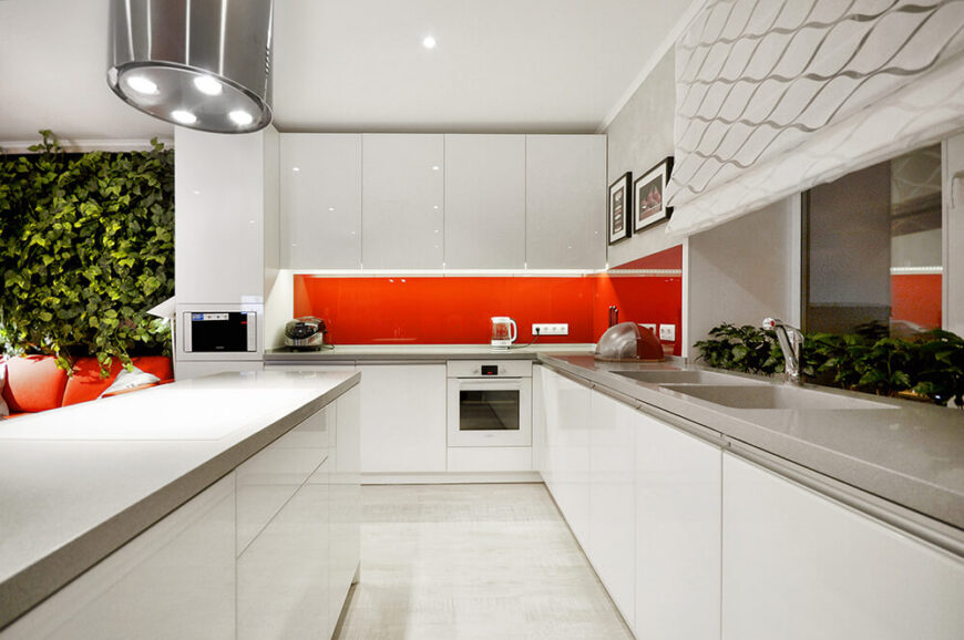 让我们来看看明亮的白色厨房，光滑的白色橱柜和亮橙色的后挡板。无硬件橱柜门创造了一个无缝的环境。