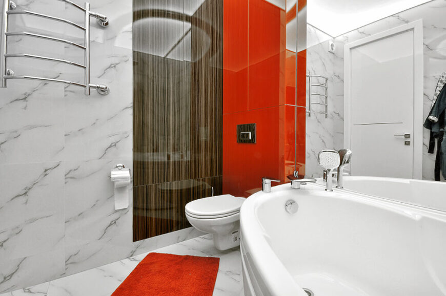 浴室结合了许多在家里其他地方看到的元素，包括光滑的玻璃，大胆的橙色色调，和一点天然木材。