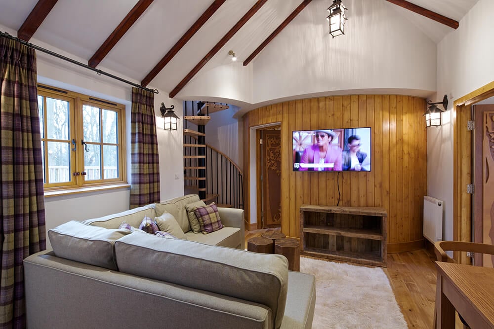 工匠客厅提供木木板地板，与安装有平板电视的强调墙相辅相成，教堂天花板衬有深色木梁。