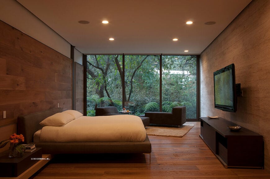 主卧室是另一个温暖的空间，包裹着丰富的木镶板。这使得一个非常有凝聚力的外观，与外部郁郁葱葱的自然形成对比，通过通高的窗户看到。
