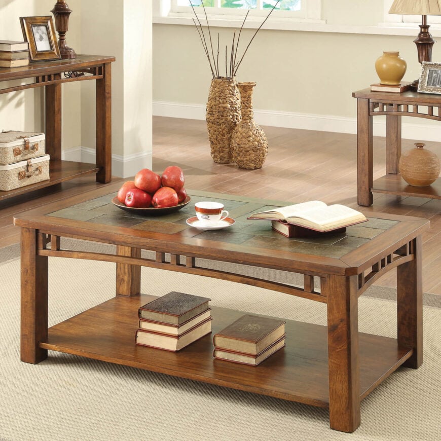 这是另一个优雅、丰富的木质咖啡桌，桌面有一种微妙但华丽的口音。在这里，我们看到石板瓷砖覆盖了大部分的表面区域，周围是厚木梁。这张桌子的特点是在腿之间的边缘有一些装饰，但它并不挑剔，也很光滑，保持了真实的风格。