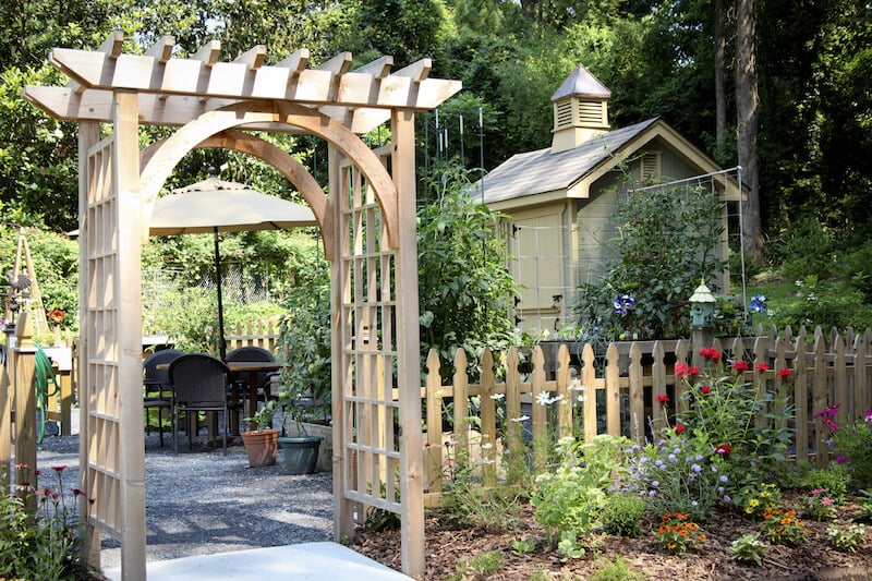 这个简单的木质凉亭休息入口处的后院天井到一边。院子里由一个简单的尖桩篱栅平方了。